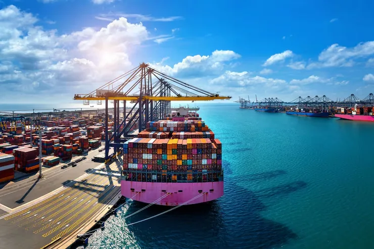 Container ship at berth under quay cranes beside turquoise water